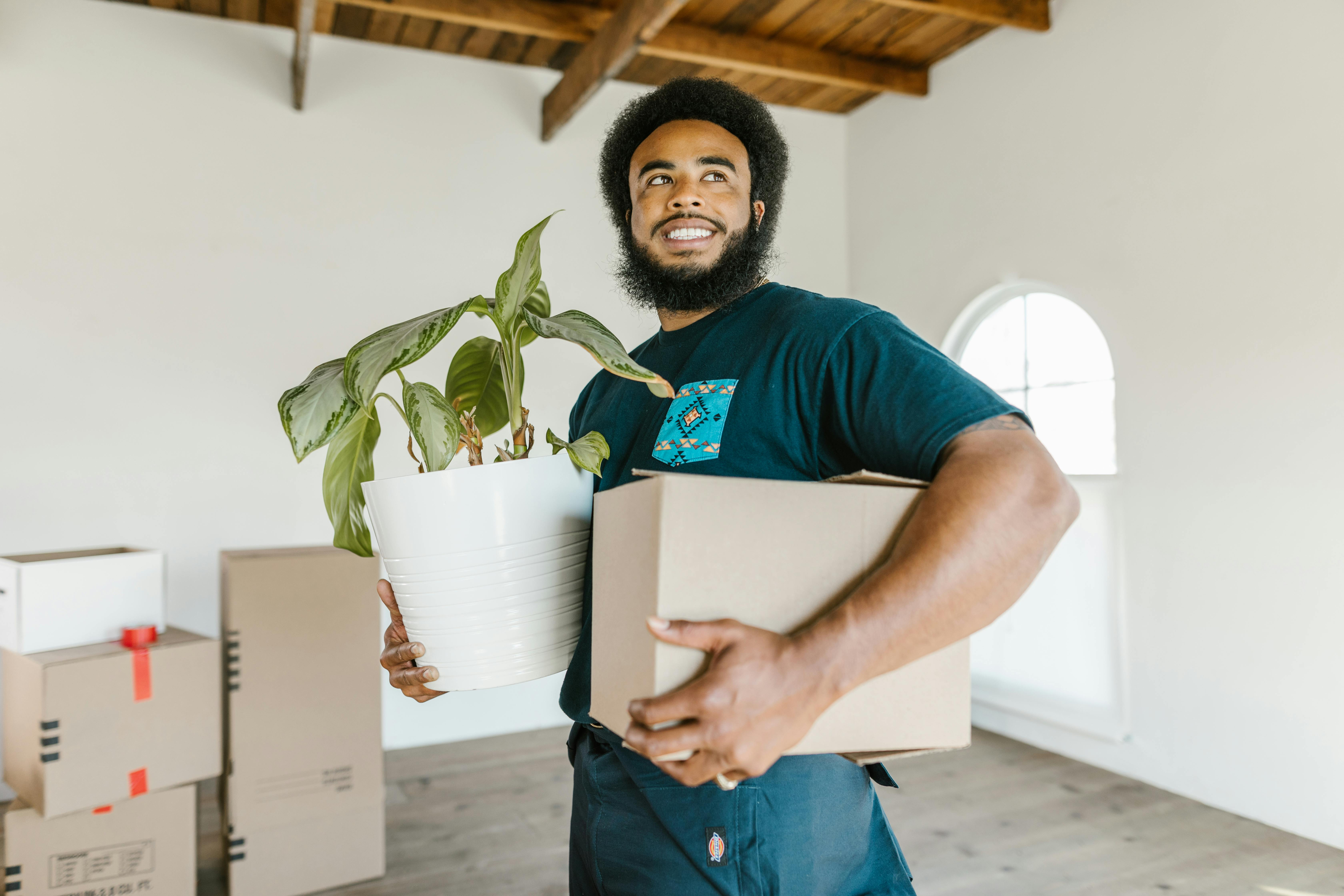 Man holding moving boxes and plants