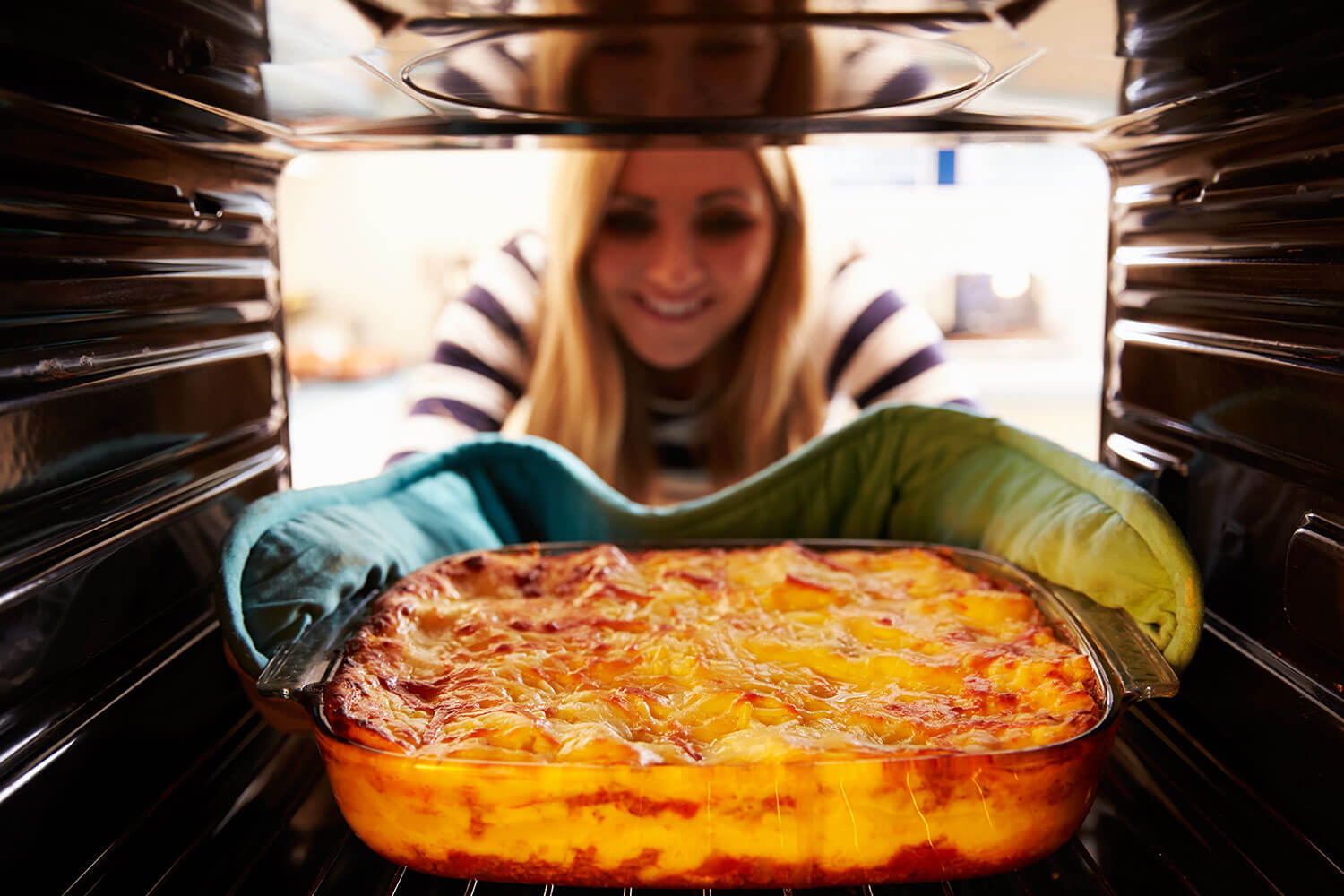 Woman taking dish from oven