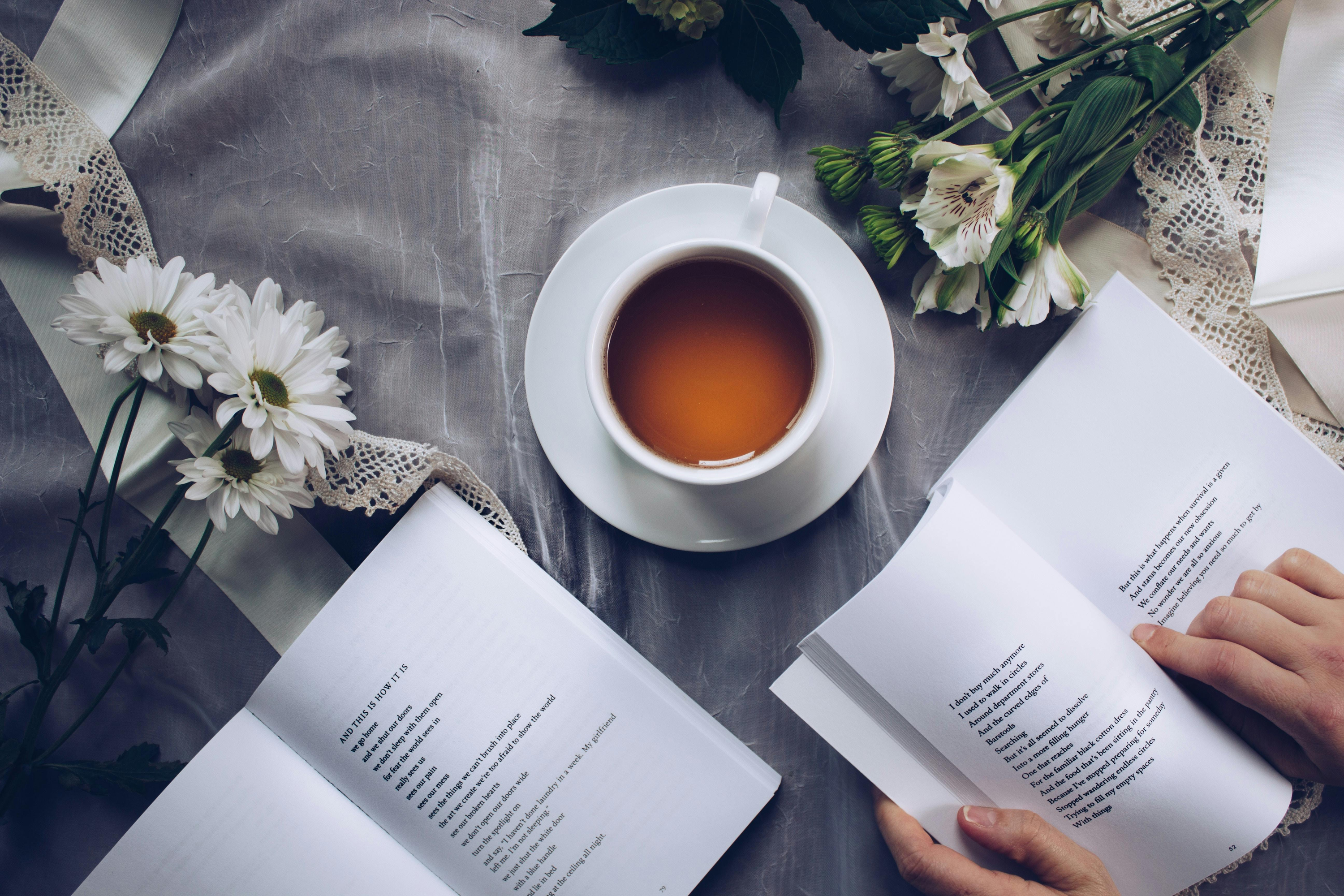 Cup of tea and open books on table