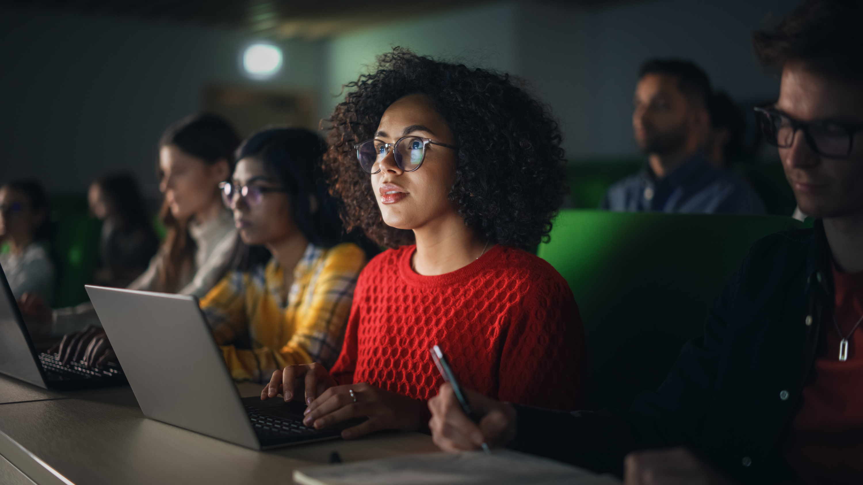 Black student sat taking notes on laptop