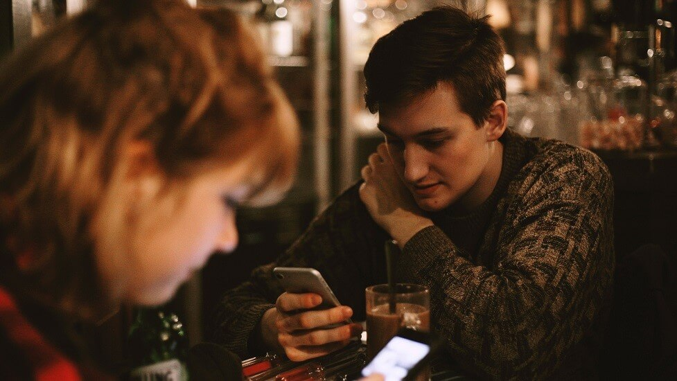 Man on his phone and woman in foreground