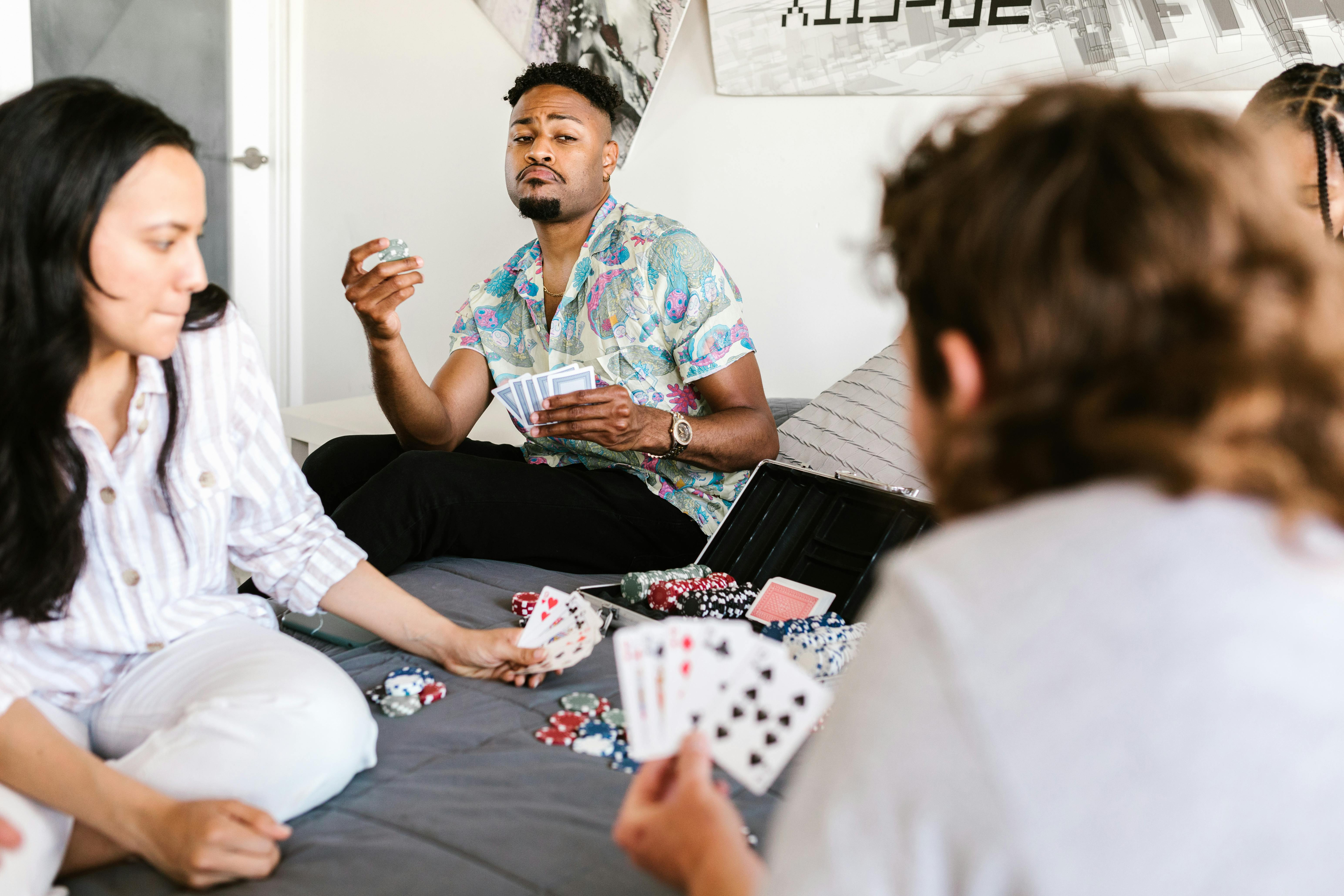 Group of people sat on bed playing cards