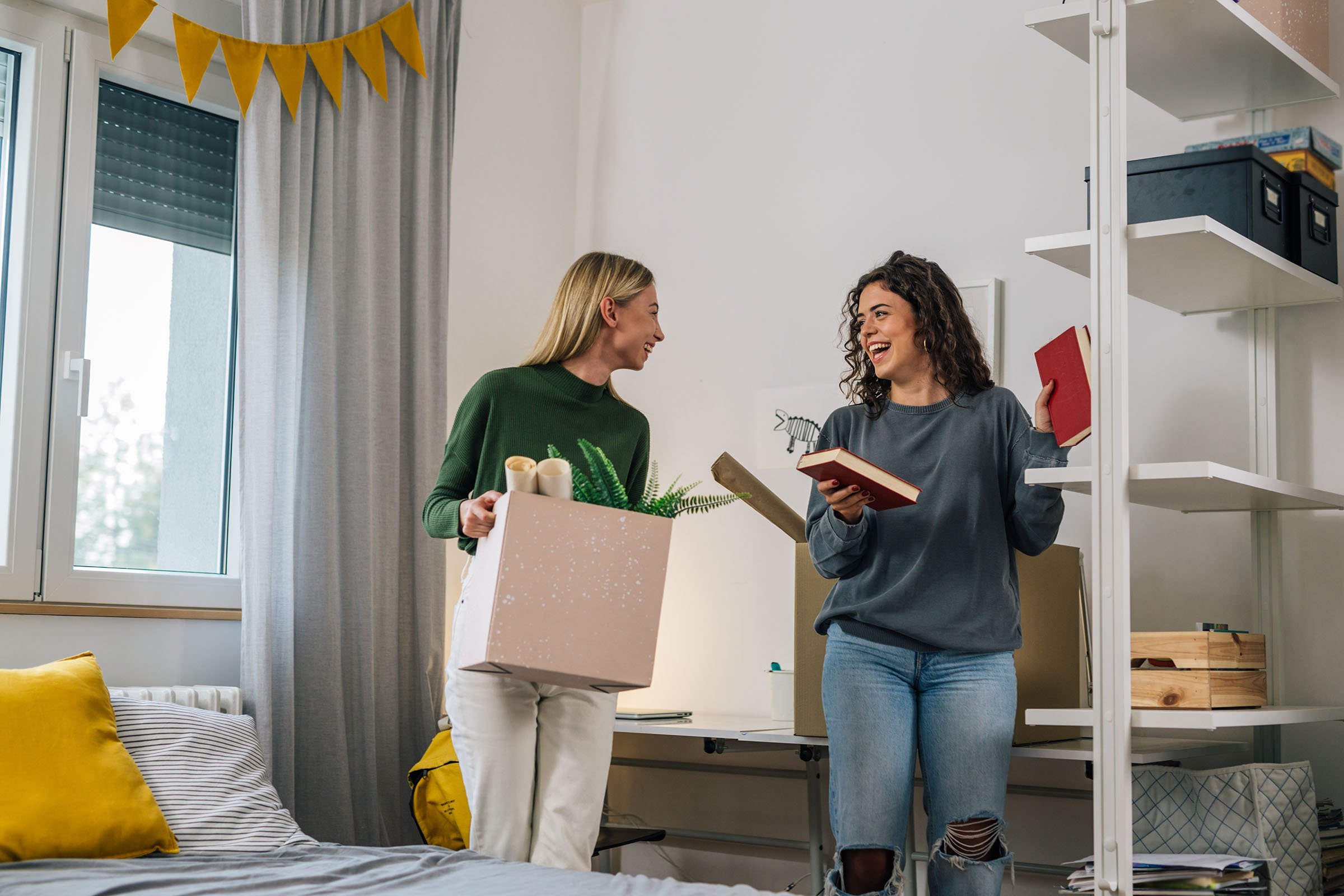 2 women packing books in bedroom