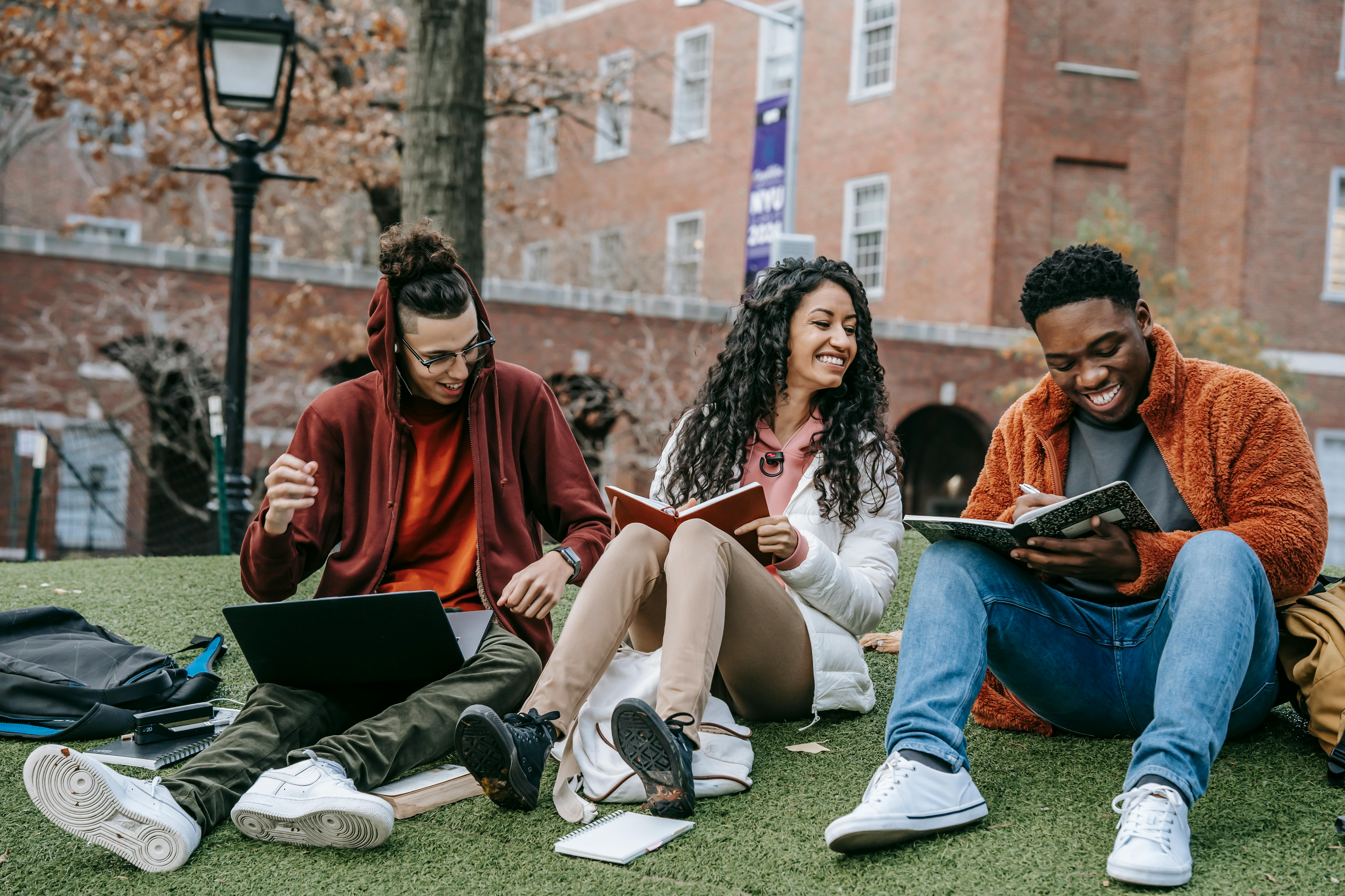 Three students sat outside on the grass