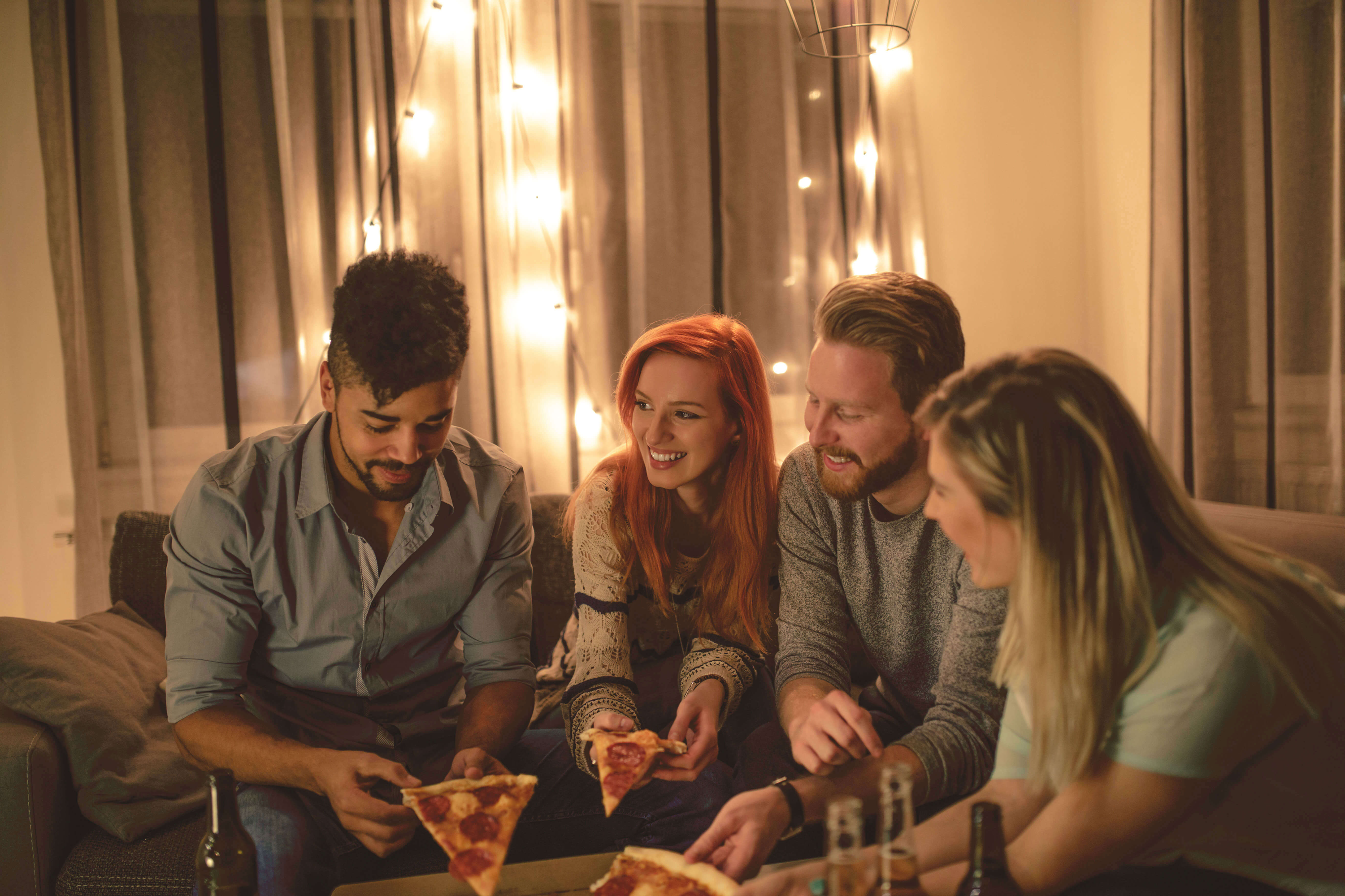 Group of friends sat around eating pizza